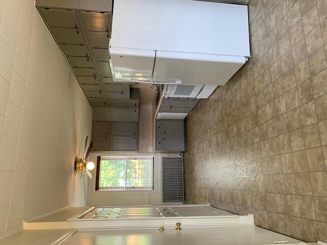 A room with a large window and a white ceiling with a vent.